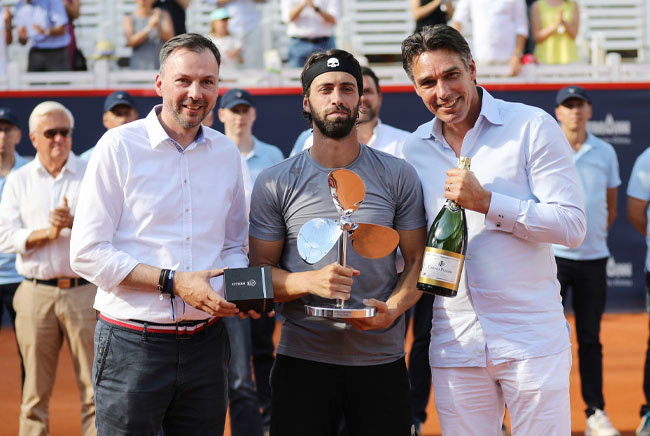 Hendrik Kampmann, Nikoloz Basilashvili holding the winner's prize (winner of the German Opens) and Michael Stich smile into the camera